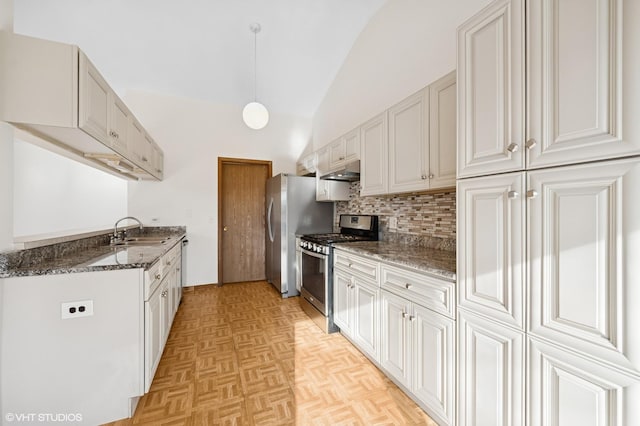 kitchen featuring backsplash, under cabinet range hood, dark stone counters, stainless steel appliances, and a sink