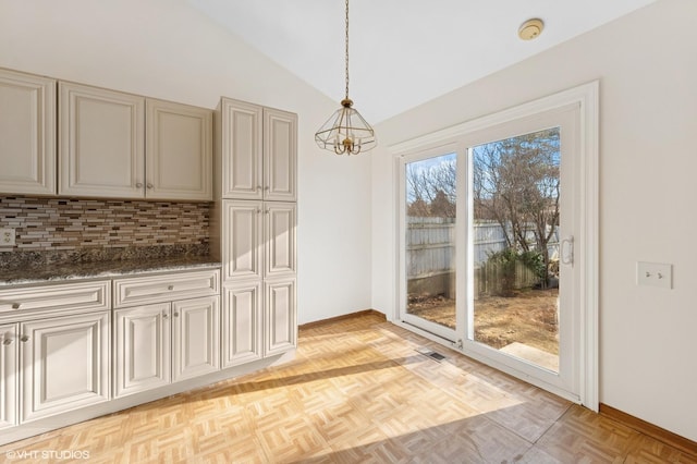 unfurnished dining area featuring vaulted ceiling, a notable chandelier, and baseboards