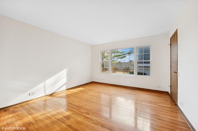 unfurnished room with visible vents, light wood-style flooring, and baseboards