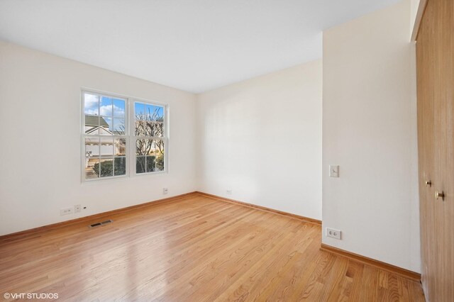 spare room featuring visible vents, baseboards, and wood finished floors