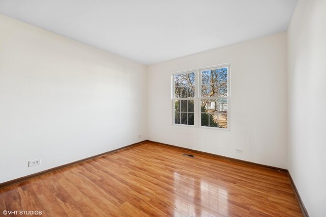 spare room featuring visible vents, baseboards, and wood finished floors