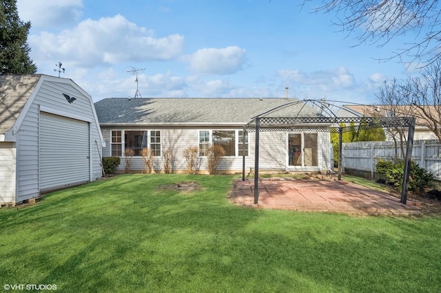 rear view of property with an outbuilding, fence, roof with shingles, a patio area, and a lawn