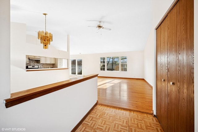 corridor with baseboards, high vaulted ceiling, an inviting chandelier, and parquet flooring