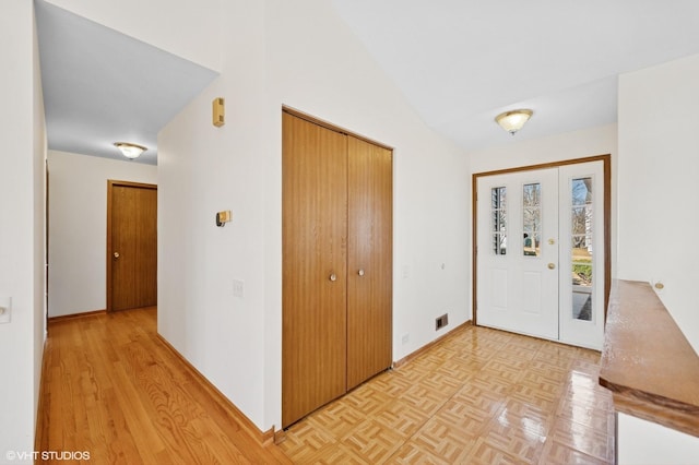 foyer entrance with lofted ceiling, parquet flooring, baseboards, and visible vents