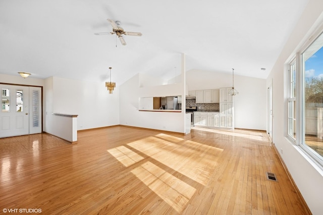 unfurnished living room with baseboards, light wood-style flooring, ceiling fan with notable chandelier, and lofted ceiling