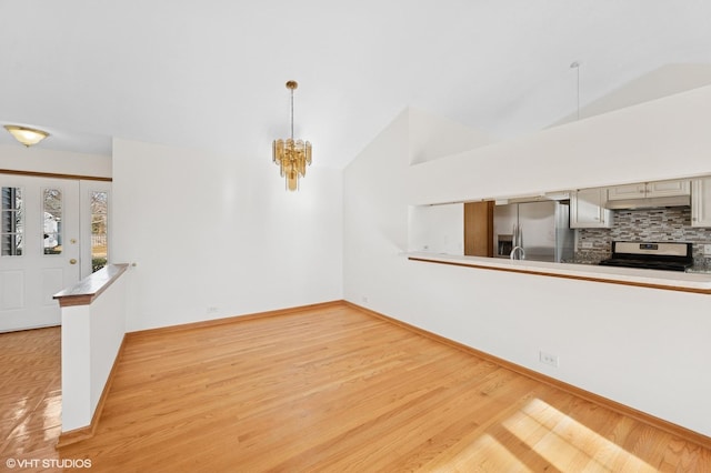 unfurnished dining area with a chandelier, baseboards, light wood-style flooring, and vaulted ceiling