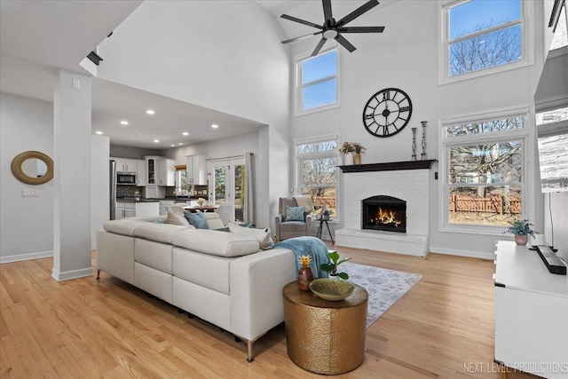 living area with baseboards, plenty of natural light, light wood-style flooring, and a fireplace