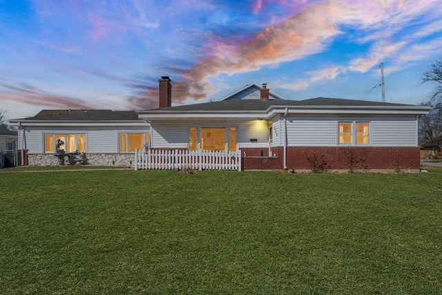 ranch-style home featuring a lawn, covered porch, and a chimney