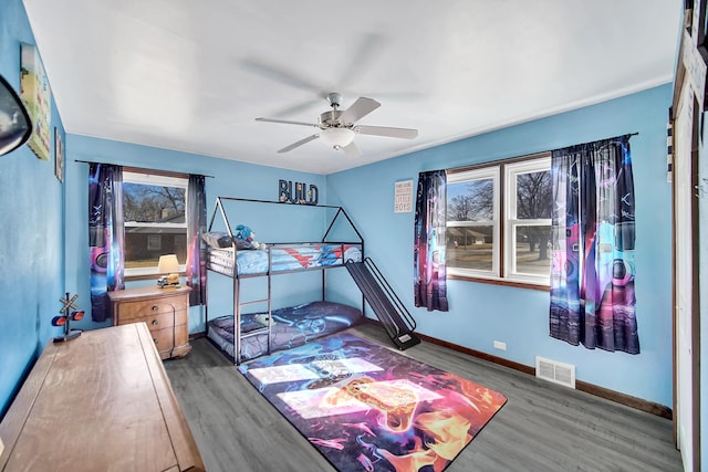 bedroom featuring ceiling fan, wood finished floors, visible vents, and baseboards