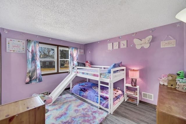 bedroom featuring visible vents, a textured ceiling, and wood finished floors