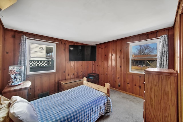 carpeted bedroom featuring wooden walls, visible vents, and baseboards