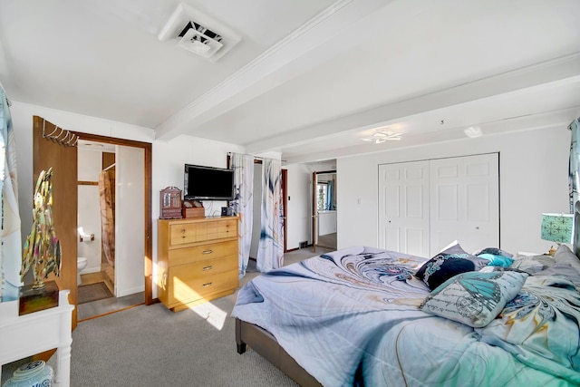 bedroom featuring visible vents, beam ceiling, light carpet, ensuite bath, and a closet