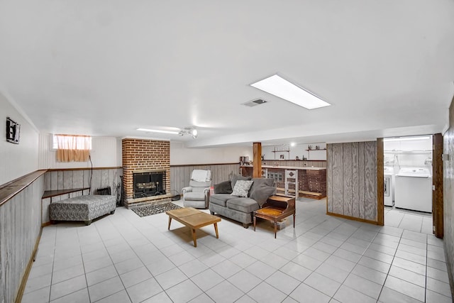 living room featuring washer and dryer, visible vents, wainscoting, and a fireplace