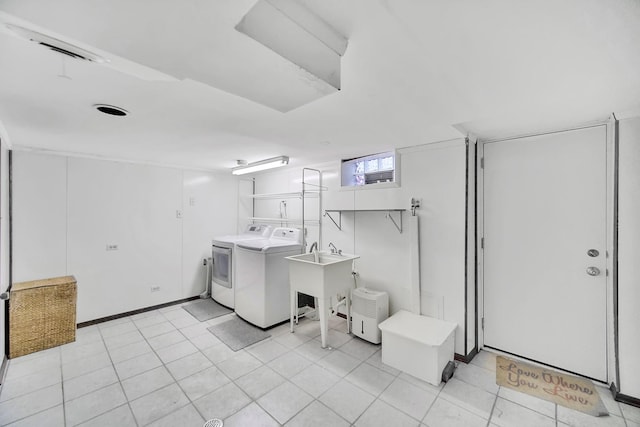 laundry room featuring washer and clothes dryer, laundry area, light tile patterned floors, and a sink