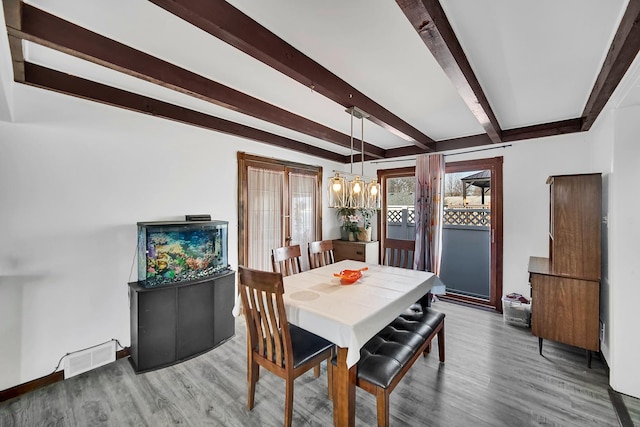 dining room with beam ceiling, visible vents, a notable chandelier, and wood finished floors