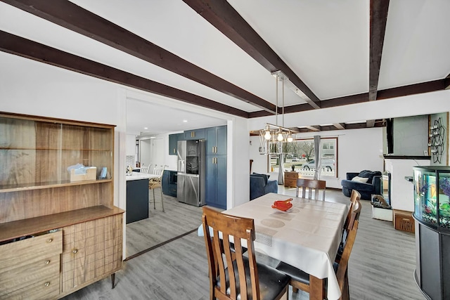 dining room featuring beam ceiling, a chandelier, and light wood finished floors