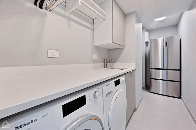 laundry room with light tile patterned flooring, laundry area, separate washer and dryer, and a sink