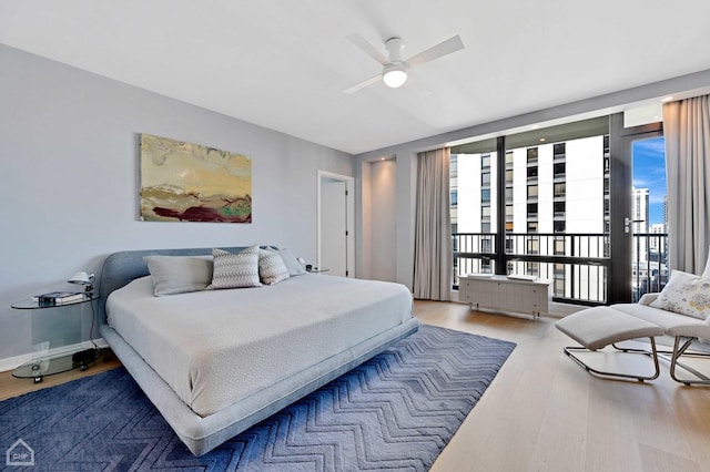 bedroom with access to exterior, radiator, ceiling fan, and wood finished floors