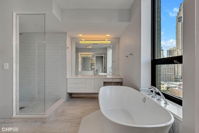 bathroom featuring vanity, a soaking tub, recessed lighting, a stall shower, and a view of city