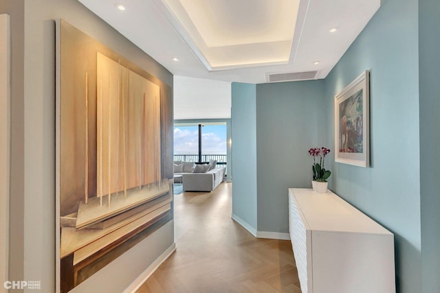 hall featuring visible vents, recessed lighting, baseboards, and a tray ceiling