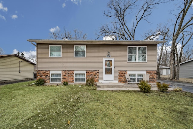 bi-level home featuring brick siding, a patio, and a front yard