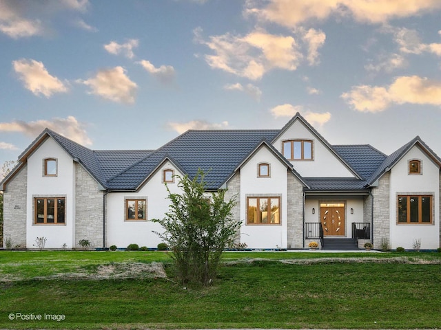 view of front facade featuring a standing seam roof, a front yard, stone siding, and metal roof