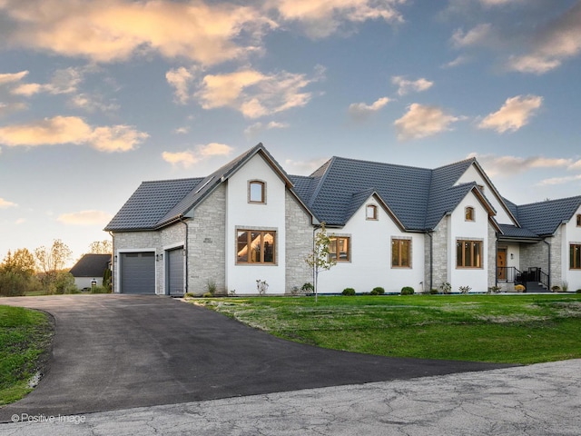 view of front of home featuring stone siding, driveway, a tile roof, and a front yard