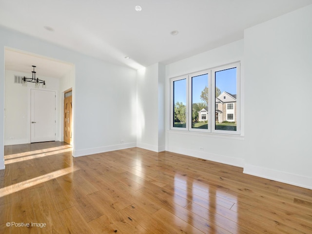 unfurnished room featuring visible vents, baseboards, light wood-style floors, and a chandelier