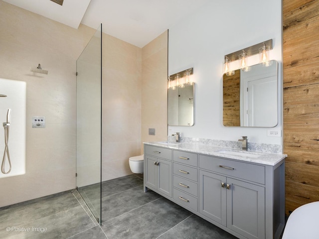 bathroom featuring double vanity, a sink, walk in shower, tile walls, and toilet