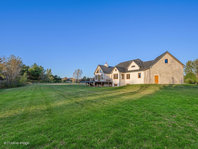 rear view of property with brick siding, a deck, and a yard