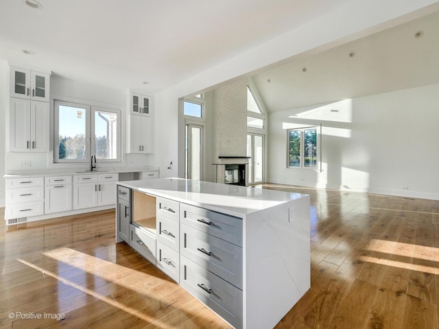 kitchen with light wood-style flooring, white cabinets, open floor plan, and a multi sided fireplace