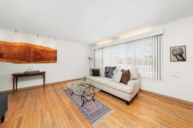 living area featuring hardwood / wood-style flooring, crown molding, baseboards, and track lighting