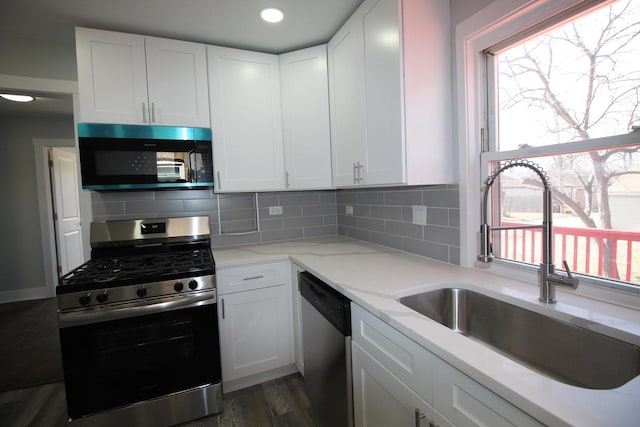 kitchen with white cabinets, backsplash, appliances with stainless steel finishes, and a sink