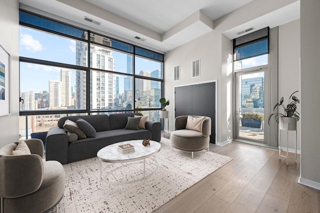 living area with a view of city, a healthy amount of sunlight, visible vents, and wood-type flooring