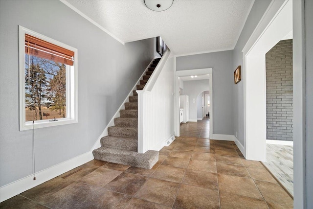 foyer with arched walkways, visible vents, stairway, and a textured ceiling