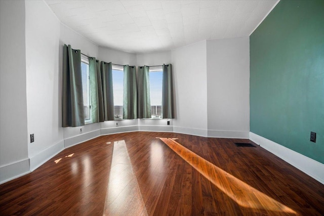 spare room with visible vents, baseboards, and wood finished floors