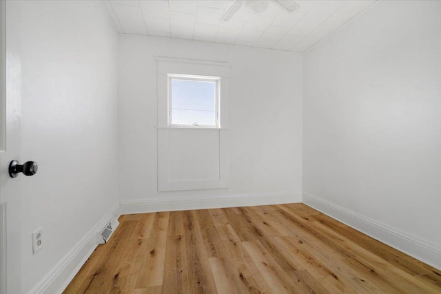 empty room with baseboards, visible vents, and light wood finished floors