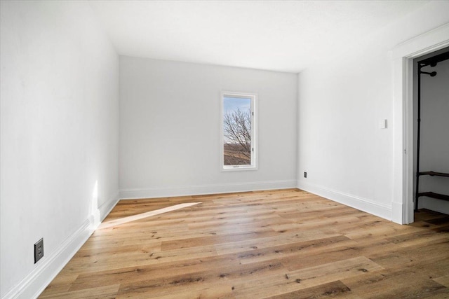 spare room featuring baseboards and wood finished floors