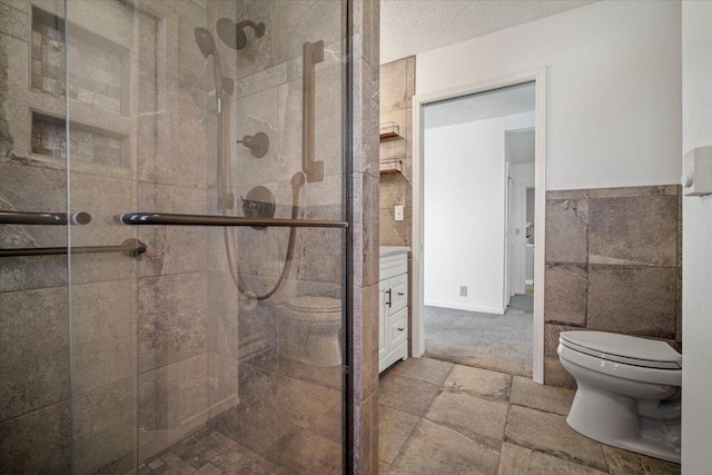 bathroom featuring a stall shower, stone tile flooring, wainscoting, tile walls, and toilet