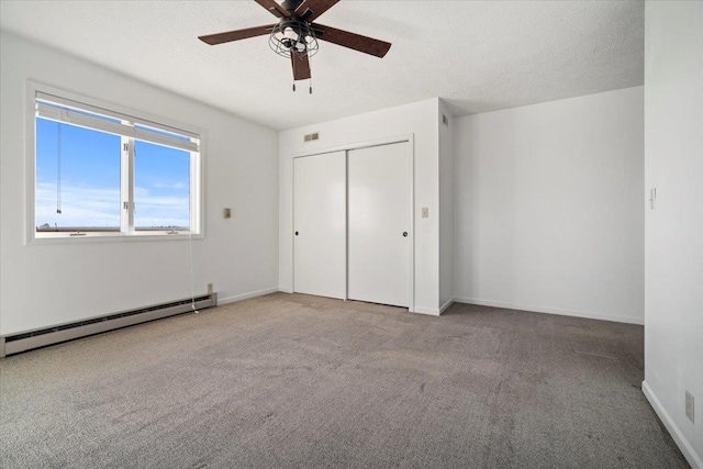 unfurnished bedroom with baseboards, carpet floors, a closet, a textured ceiling, and a baseboard heating unit