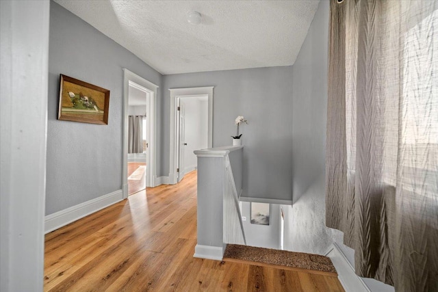 stairway with baseboards, a textured ceiling, and wood finished floors