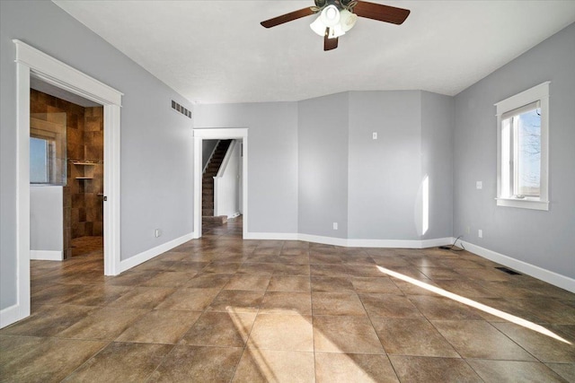 spare room featuring visible vents, baseboards, ceiling fan, and stairs