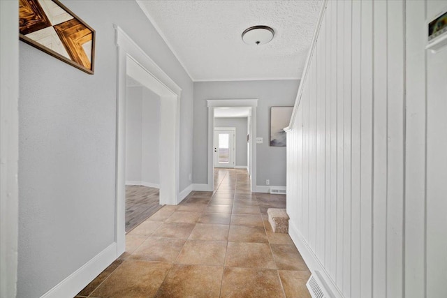 hallway with visible vents, baseboards, and a textured ceiling