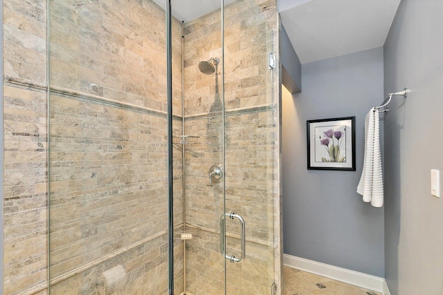 bathroom with a shower stall and baseboards