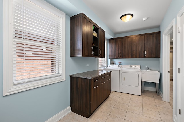 clothes washing area featuring baseboards, cabinet space, separate washer and dryer, and light tile patterned flooring