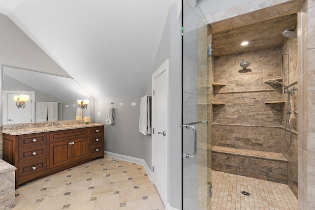 full bath featuring a stall shower, vanity, baseboards, and vaulted ceiling