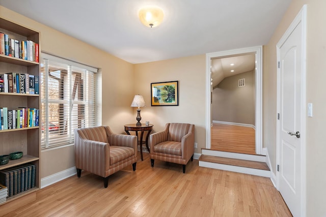 living area with visible vents, wood finished floors, and baseboards