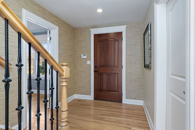 entrance foyer with visible vents, baseboards, wood finished floors, and stairs