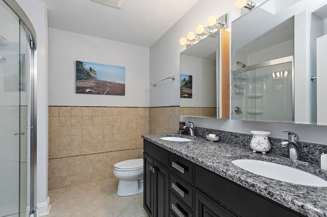 full bathroom with tile patterned flooring, a stall shower, tile walls, and a sink