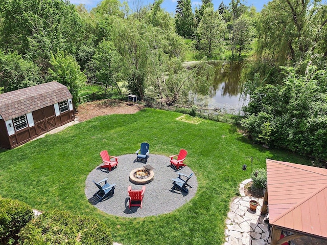 view of yard featuring a patio area, a water view, an outdoor structure, and an outdoor fire pit